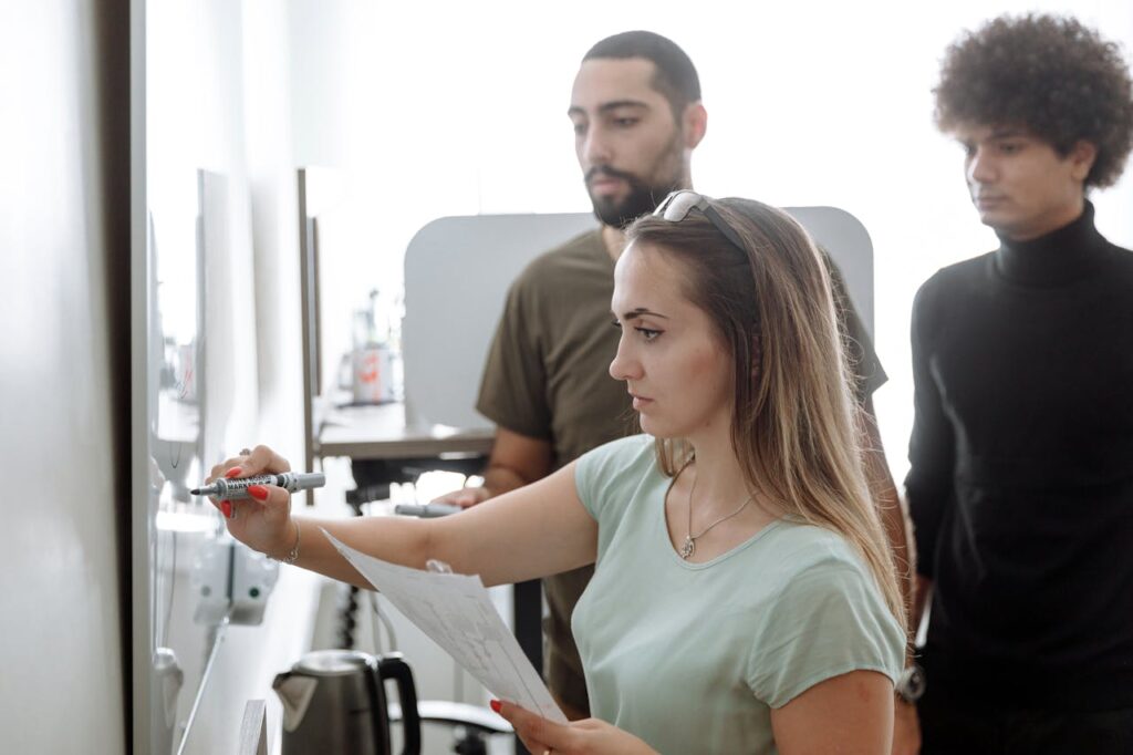 3 Individuals Discussing infront of a white board